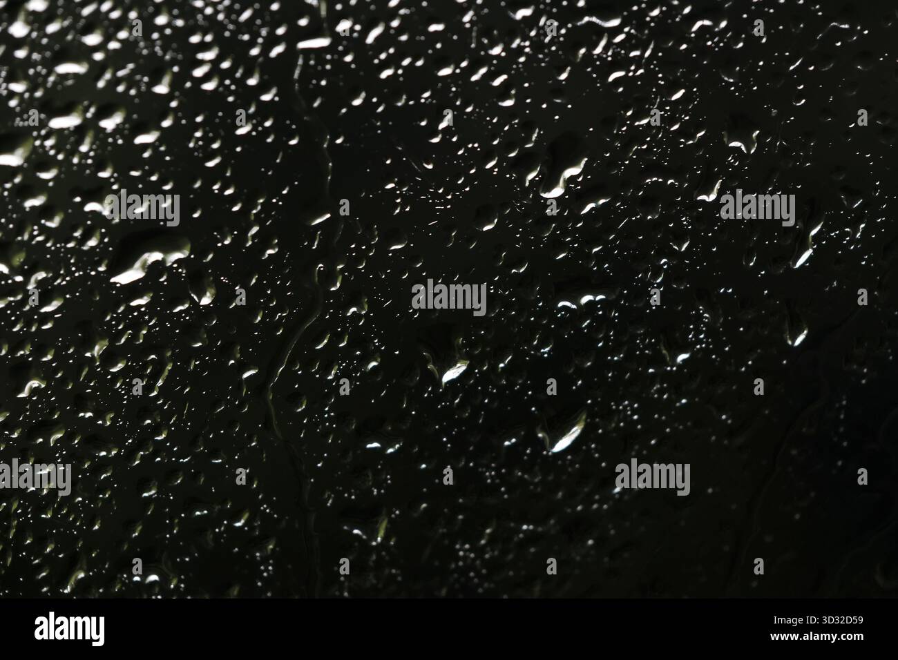 Moody abstrakter Hintergrund von Wasserregentröpfchen auf dunkelschwarzer Oberfläche. Nahaufnahme der Texturansicht erzeugt ein ruhiges Gefühl von Kondensation am Fenster Stockfoto