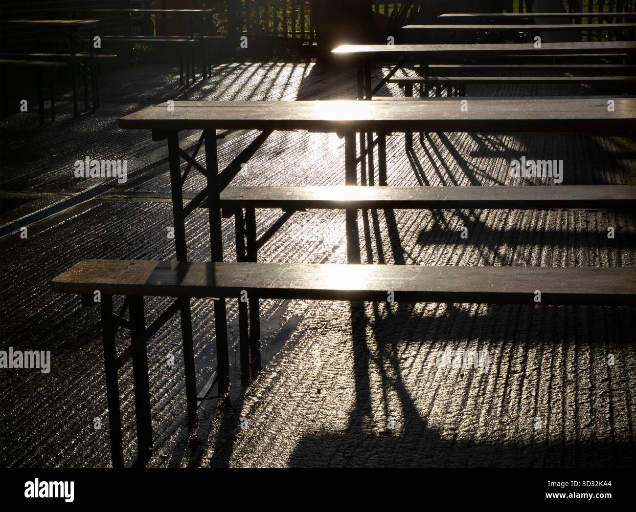 Unerwarteter Anblick im Sandford Industrial Estate - abstrakte Muster von Licht und Schatten bei Sonnenaufgang. Das ist ein ziemlich langweiliger Ort, voller Fabriken, Garagen und dergleichen. Es bietet jedoch ein beeindruckendes geselliges Backhaus, das Brot, Gebäck und andere Köstlichkeiten zubereitet. In der Tat ist es vor Ort ziemlich berühmt geworden. Diese Bänke sitzen draußen, um im Sommer unter freiem Himmel zu essen. Im Winter sind sie jedoch verlassen. Alles, was Sie sehen können, sind diese wunderschönen Muster von Licht und Schatten beim ersten Licht. Stockfoto