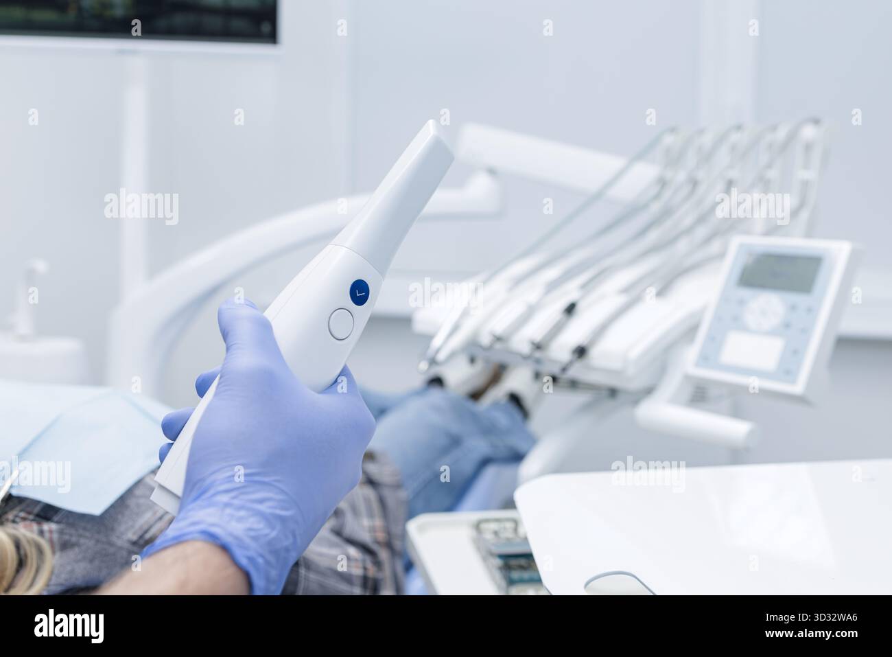 Der Zahnarzt hält einen intraoralen Scanner neben einem Patienten und erfasst einen digitalen Abdruck für die CADCAM-Behandlungsplanung in einer modernen Klinik. Stockfoto