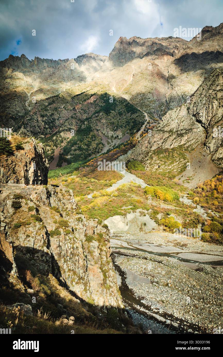 Steile Klippen und wilde Berghänge, beleuchtet von dramatischem Sonnenlicht im georgischen Kaukasus. Unberührte Natur, Kiesbetten und abgelegene Wanderwege Stockfoto