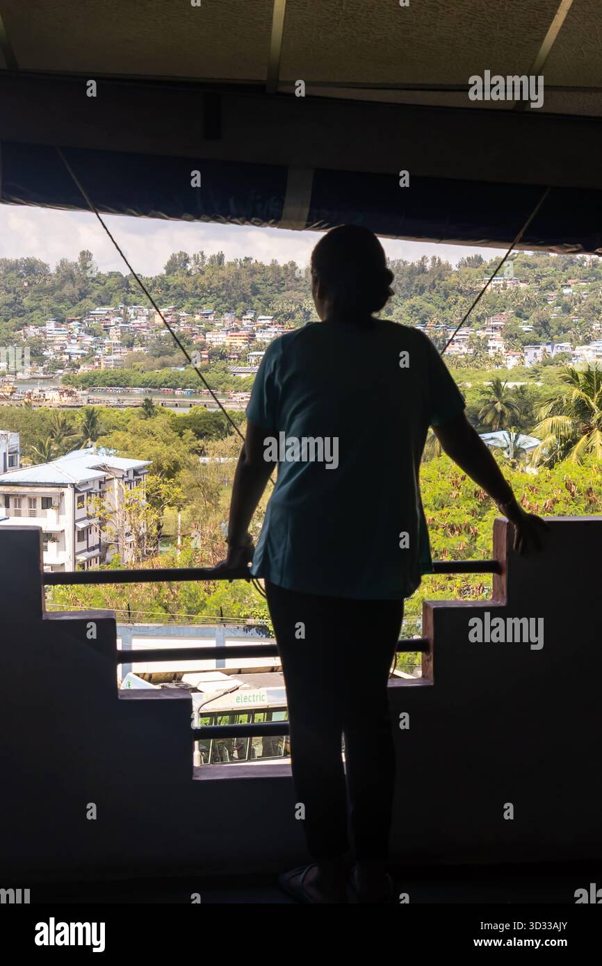Eine Frau, die auf einem Balkon mit Blick auf den Hügel steht, wurde am Hafen blair Andaman Nicobar Islands, Indien, aufgenommen. Stockfoto
