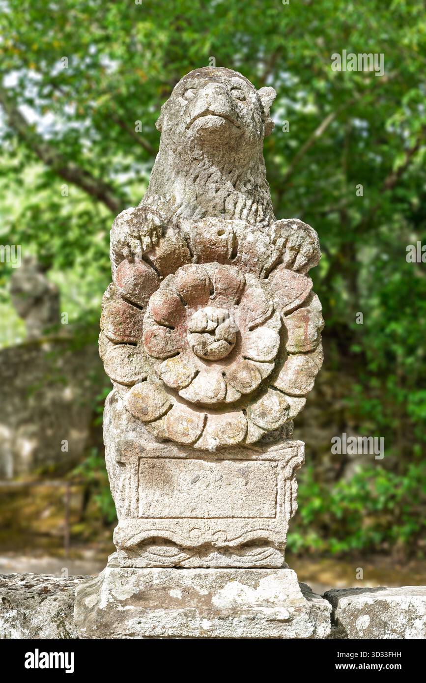 Italien - Bomarzo - Sacro Bosco - Orsi-Sockel, Bärenwappen mit einem Blumenrunder auf quadratischer Basis, Wappenwappen in Peperino geschnitzt Stockfoto