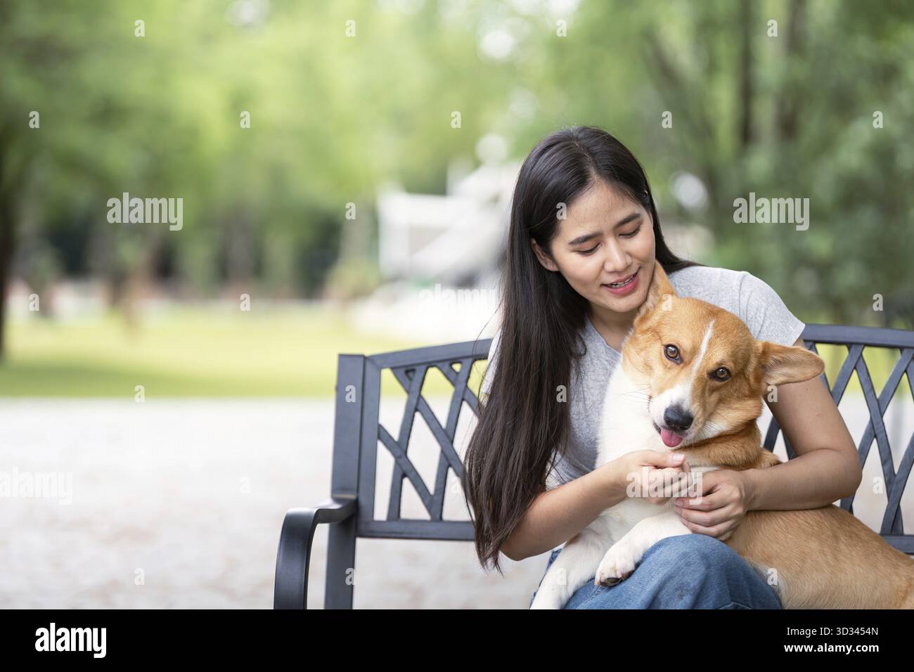 Eine junge Frau kuschelt ihren Corgi-Hund auf einer Bank, um ihre emotionale Verbindung und Gesellschaft hervorzuheben Stockfoto