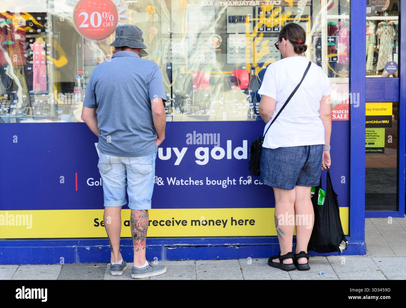 Ein junges Paar, das in ein Fenster des Kaufs schaut, der Gold für Bargeld kauft und verkauft, Clacton Essex UK Stockfoto