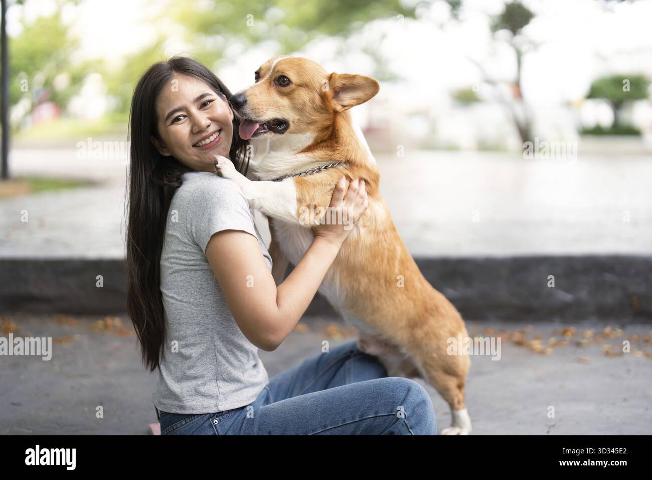 Eine junge Frau teilt eine liebevolle Umarmung mit ihrem Corgi und betont die emotionale Verbindung zwischen Haustieren und ihren Besitzern Stockfoto