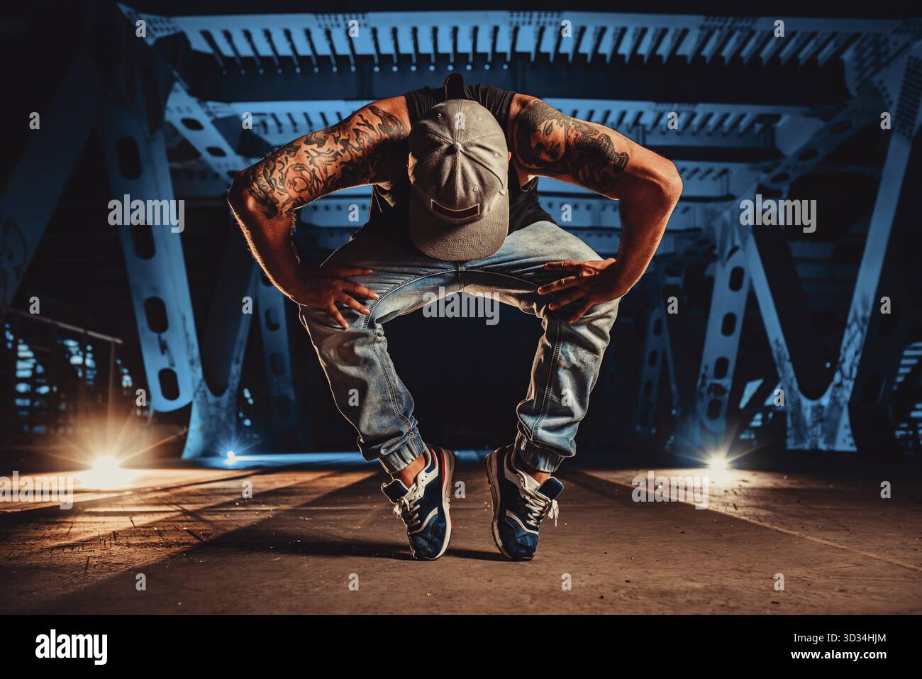 Ein junger, cooler Mann, der nachts auf einer Stadtbrücke posiert, tätowiert auf dem Körper Stockfoto