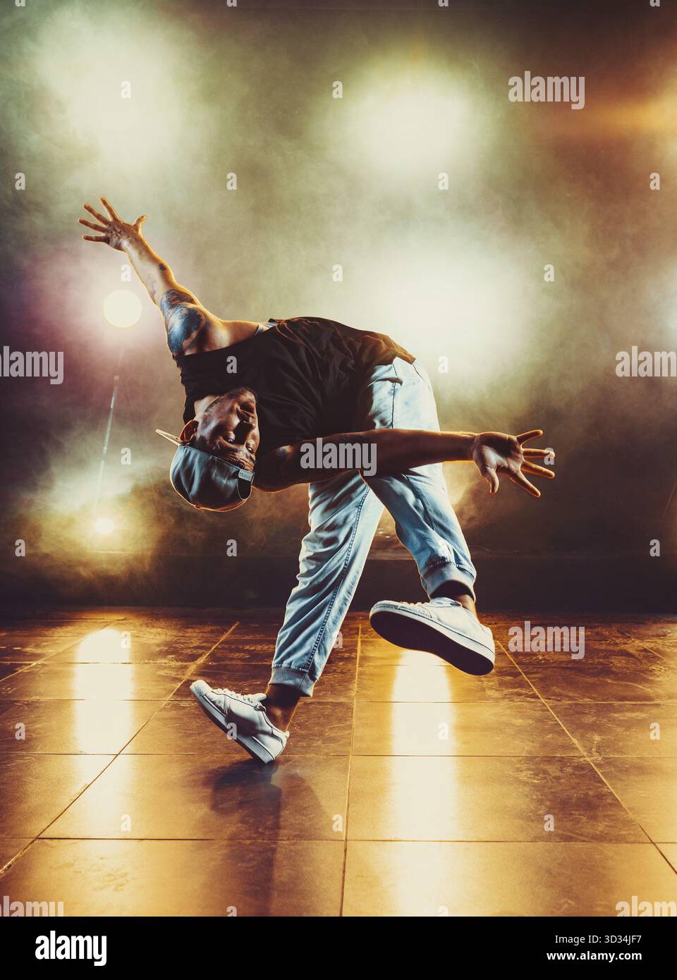 Junger Mann tanzt im Club mit Licht und Rauch. Tätowierung am Körper Stockfoto
