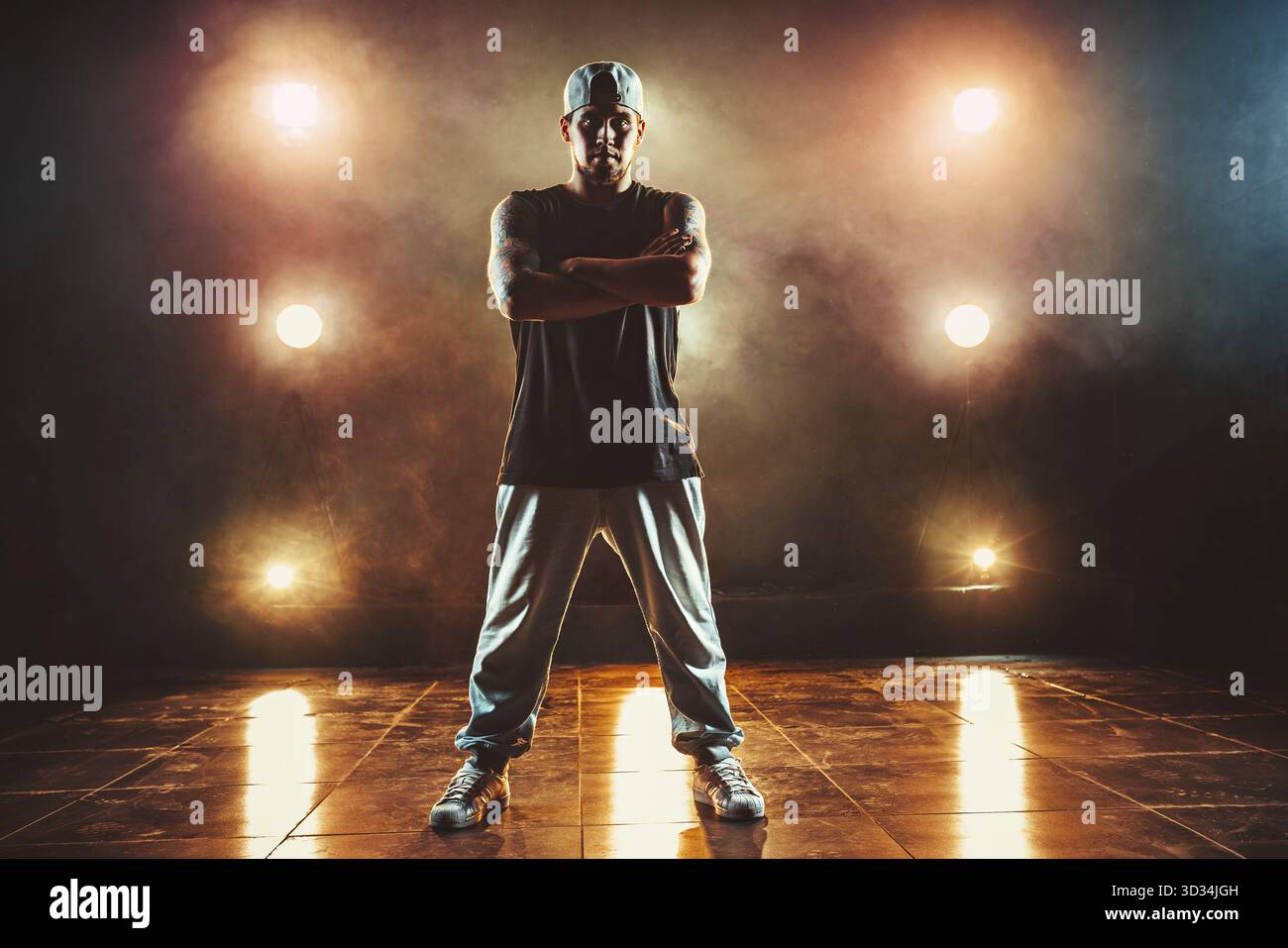Junger Coolman Breakdancer, der im Club mit Licht und Rauch steht. Tätowierung am Körper Stockfoto
