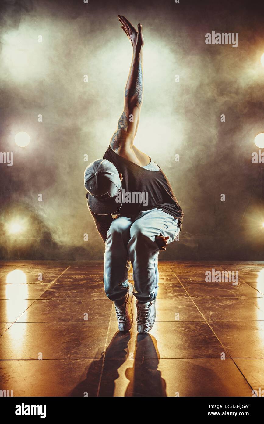 Junger coole Mann, der im Club mit Licht und Rauch tanzt. Tätowierung am Körper Stockfoto