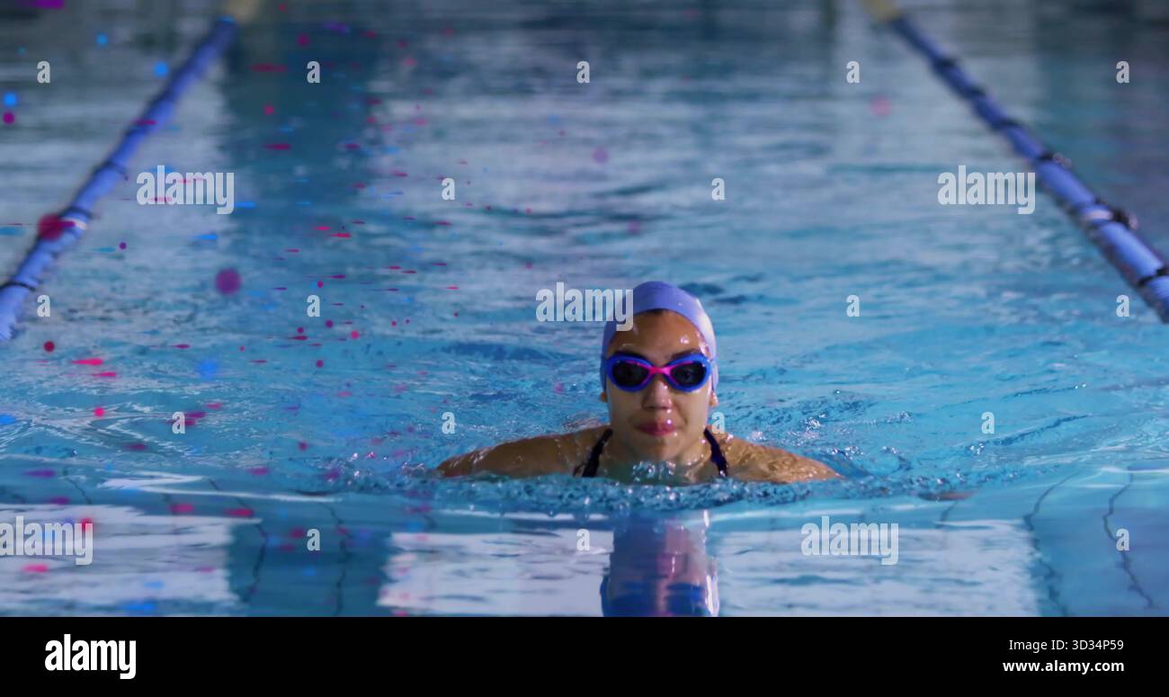 Aufstrebender Schwimmer mit violetter Mütze und Schutzbrille in der Poolbahn mit einteiligem Badeanzug und Seilen Stockfoto