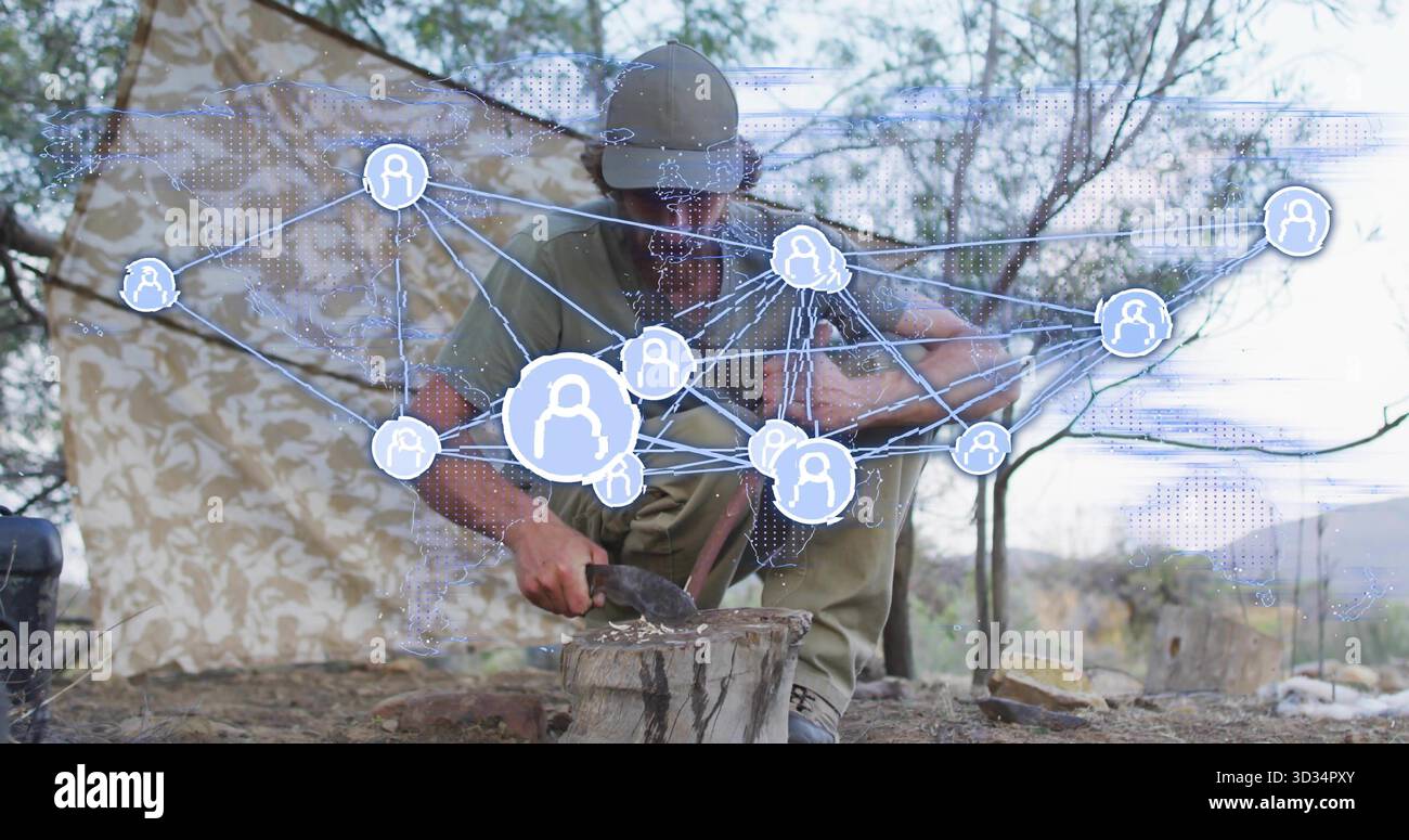 Kniender männlicher Hacker mit Beil auf Baumstümpfe im Tarnzelt, mit digitalem Netzwerk-Overlay Stockfoto
