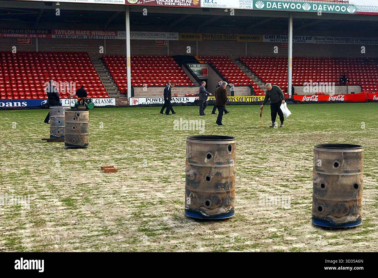 Das Personal des Walsall Football Clubs arbeitet auf dem gefrorenen Feld mit Braziers, um das Eis im Bescot Stadium zu schmelzen. Walsall V Wolverhampton Wanderers, 11. Januar 2003 Stockfoto