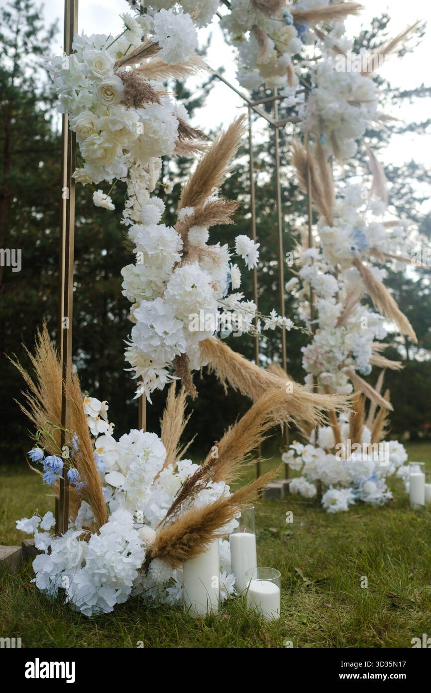 Wunderschöne Blumendekorationen mit weißen Blumen und Pampas-Gras bilden eine atemberaubende Kulisse für eine Hochzeitszeremonie im Freien in einem ruhigen, grünen Ambiente Stockfoto