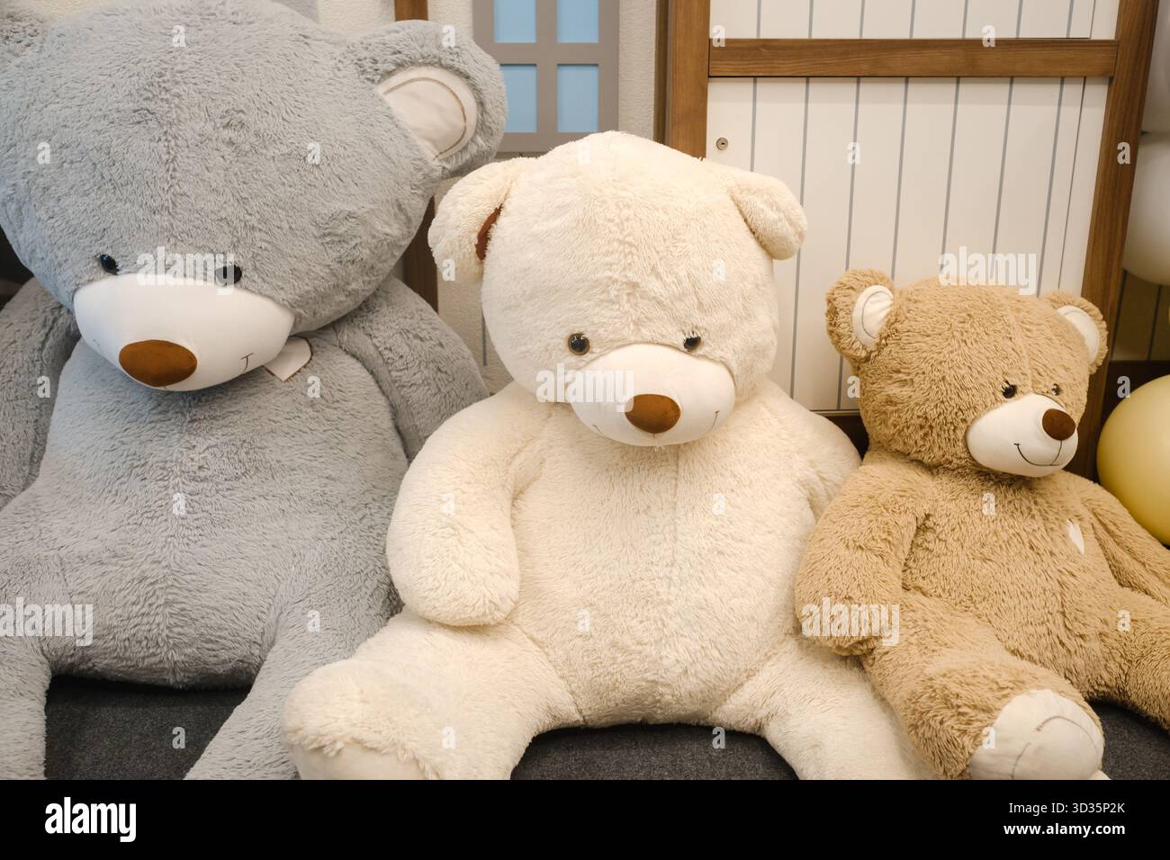Drei entzückende Teddybären in verschiedenen Größen entspannen zusammen in einem gemütlichen Innenraum. Ihre flauschigen Pelze und freundlichen Augen sorgen für eine herzerwärmende Atmosphäre Stockfoto