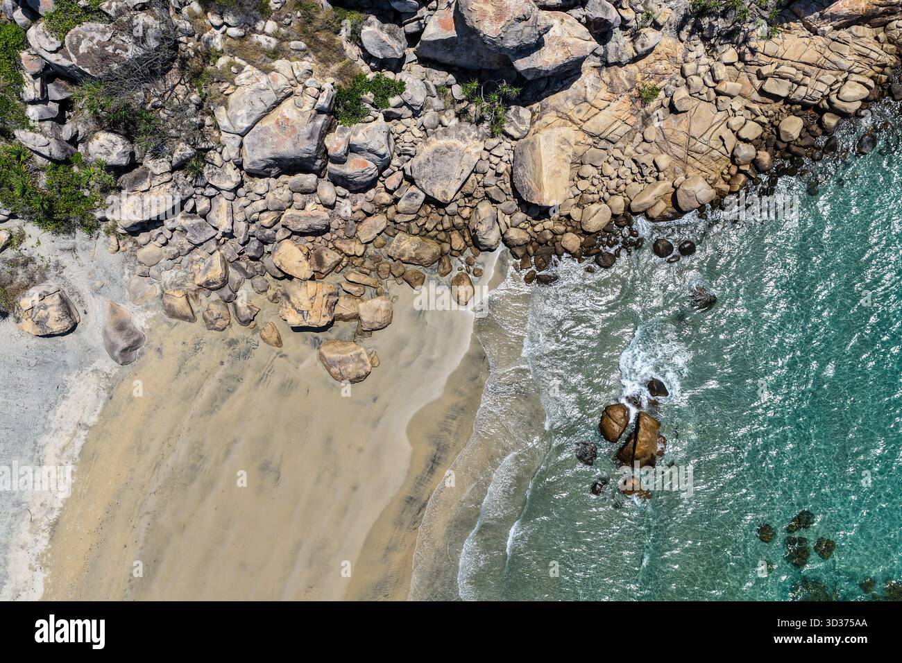 Ein Blick aus der Vogelperspektive auf die Rose Bay in Bowen, Queensland, zeigt eine atemberaubende tropische Küste mit türkisfarbenem Wasser, goldenem Sand und felsigen Landzungen. Stockfoto