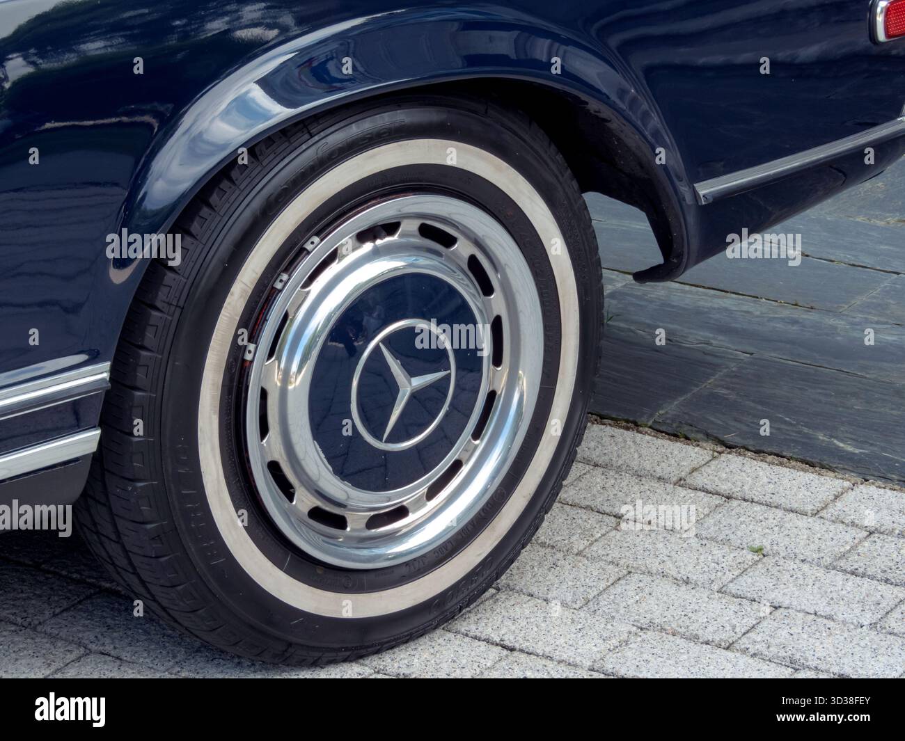 COLOMBRES, SPANIEN - 12. JULI 2025: Nahaufnahme eines klassischen Mercedes-Benz Laufrads mit Chrom-Radkappe an einem dunkelblauen Oldtimer. Retro-Automobildesign, lu Stockfoto