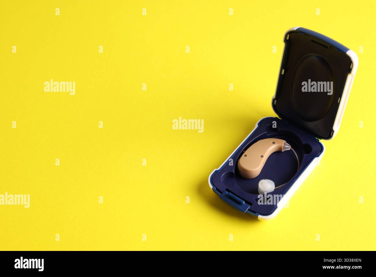Modernes Hörgerät in Box auf gelbem Hintergrund, Nahaufnahme. Leerzeichen für Text Stockfoto