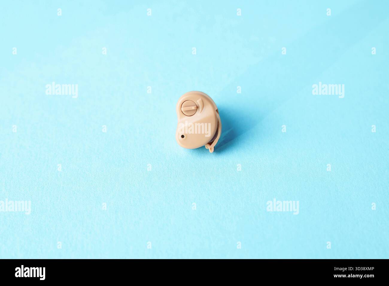 Ein modernes Hörgerät auf hellblauem Hintergrund, Nahaufnahme Stockfoto