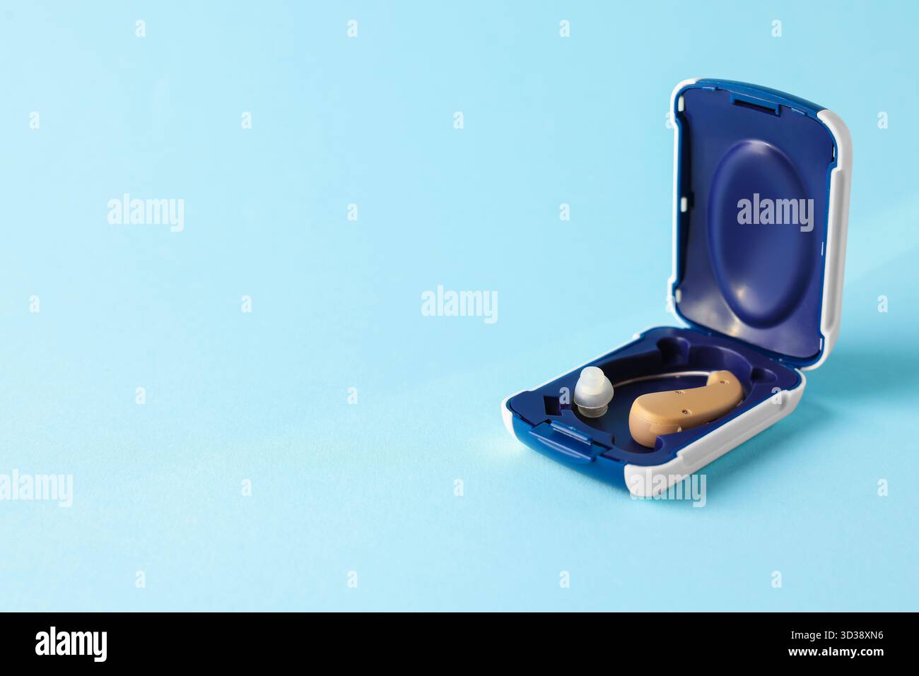 Modernes Hörgerät in Box auf hellblauem Hintergrund, Nahaufnahme. Leerzeichen für Text Stockfoto