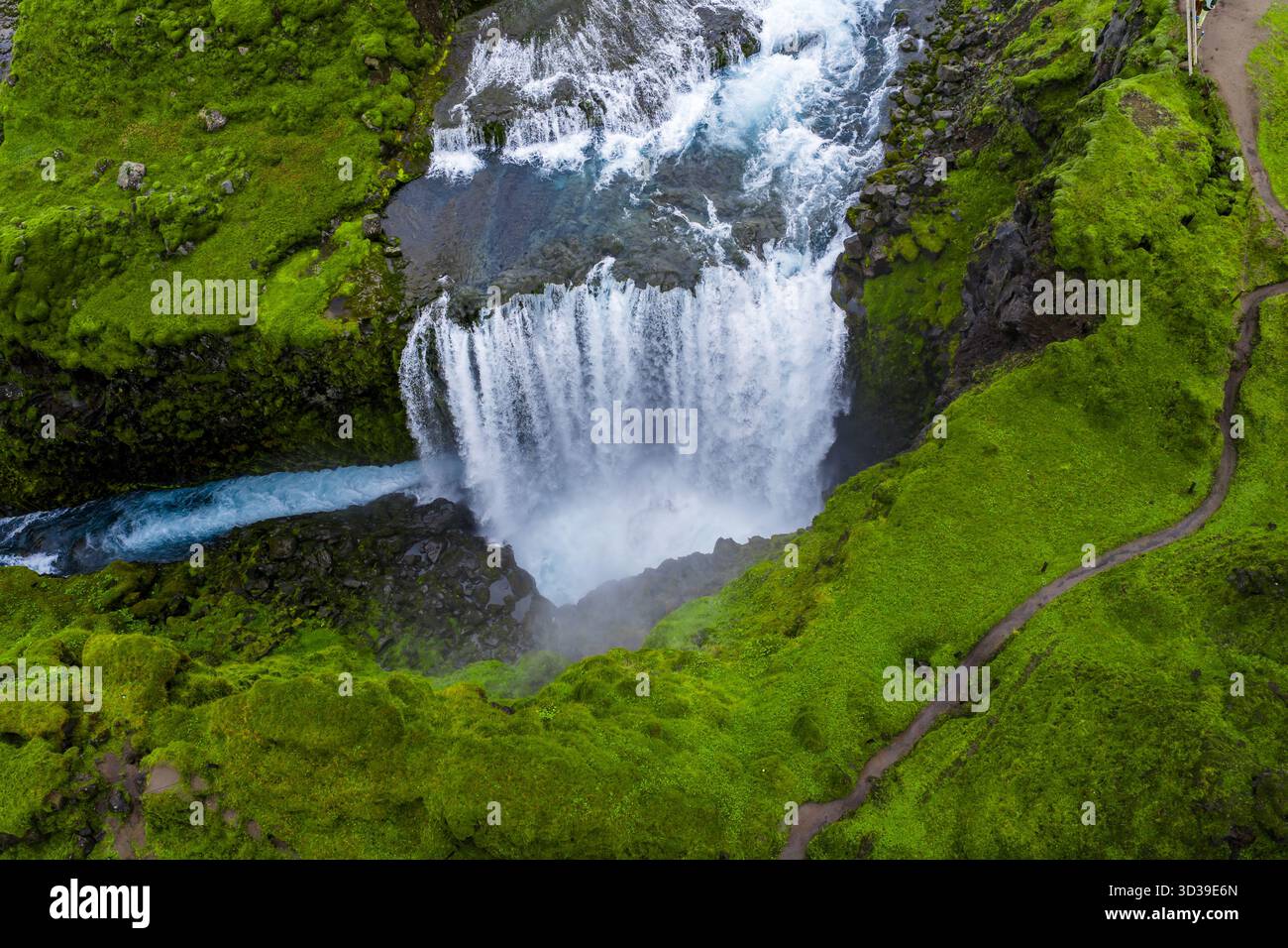 Blick von oben nach unten auf den isländischen Wasserfall und den felsigen Beckenweg Stockfoto