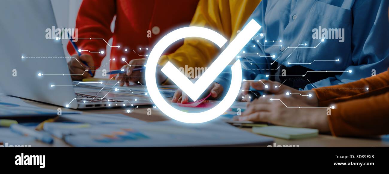 Mitglieder eines Geschäftsteams arbeiten in einem hellen Arbeitsbereich zusammen. Ein digitales Häkchen zeigt den Erfolg und die Genehmigung der Projektbemühungen an und zeigt Stockfoto