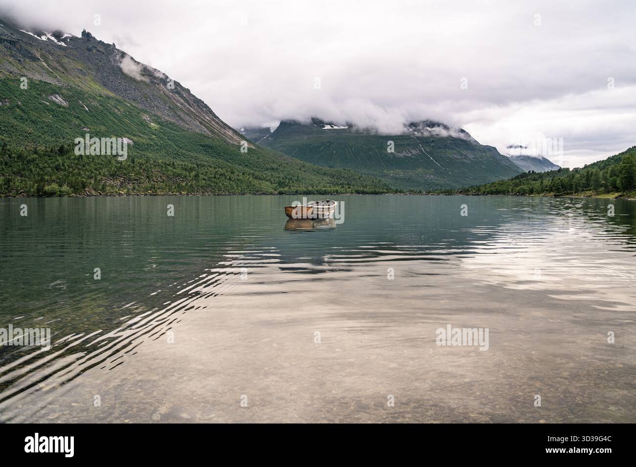 Einsames Boot ruht friedlich auf dem klaren Wasser des Sees Innerdalsvatna, umgeben von Bergen und Wolken im Innerdalen Tal Møre og Romsdal Norwegen Stockfoto