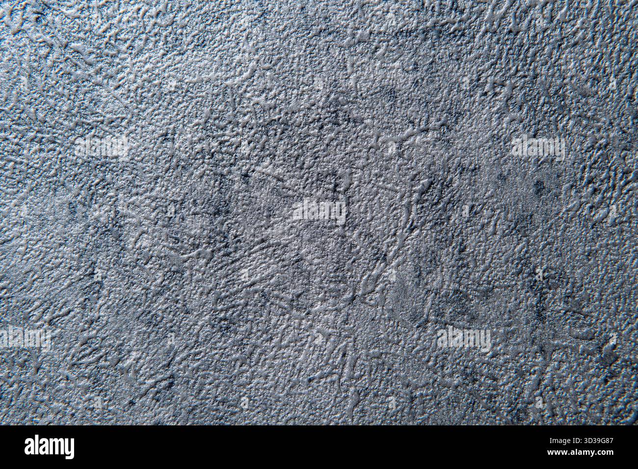 Eine Makroaufnahme mit einer rauen, holprigen, silbernen oder grauen Textur. Die lackierte Oberfläche erzeugt einen industriellen, abstrakten oder grunge-Hintergrund. Stockfoto