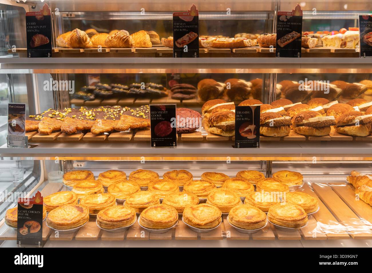 Kuala Lumpur, Malaysia - November 1,2025 : Eine Bäckerei mit einer großen Auswahl an Gebäck in einer gut beleuchteten Vitrine. Stockfoto