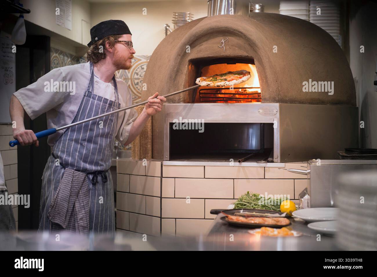 Der Koch nimmt Pizza aus dem Ofen. Stockfoto