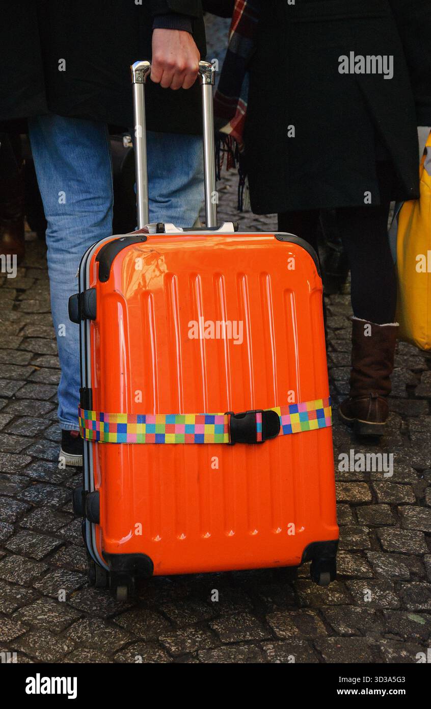 Touristen mit orangefarbenem Gepäck, die auf dem alten Pflastersteinpflaster von Montmartre spazieren. Paris, Frankreich. Stockfoto