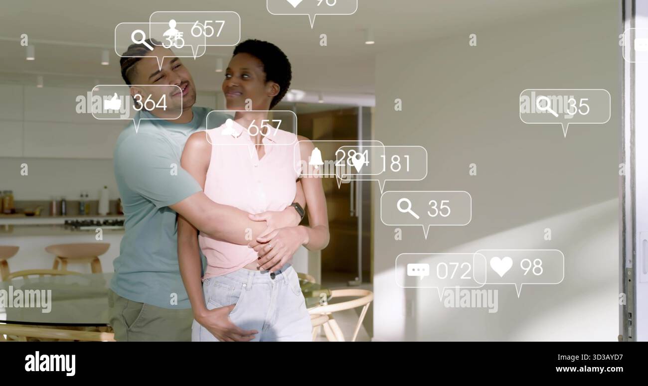 Ein Paar, das in einer hellen, modernen Küche steht, mit schwebenden Social-Media-Benachrichtigungssymbolen Stockfoto