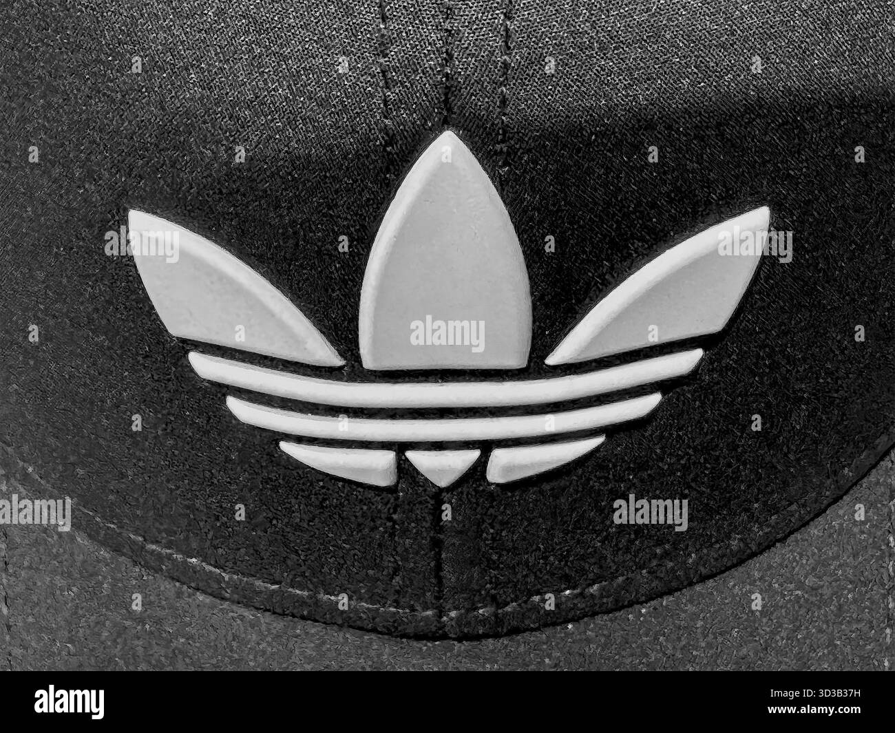 Calgary, Alberta, Kanada. April 2025. Eine Nahaufnahme des weißen Adidas Trefoil-Logos, geprägt auf einer schwarzen, strukturierten Kappe. Minimalistisch und kultig Stockfoto