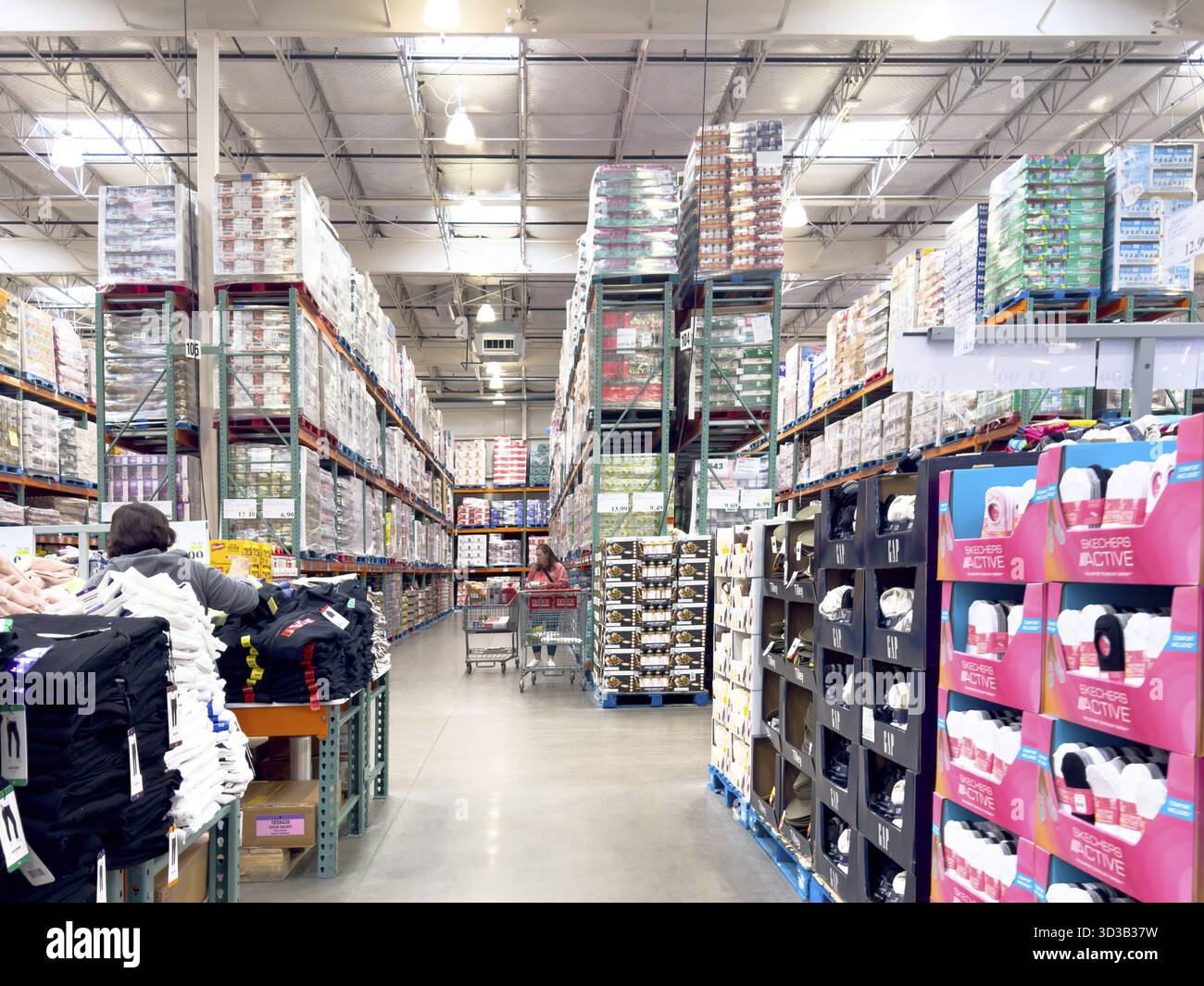 Calgary, Alberta, Kanada. April 2025. Das Innere eines Großhandelsgeschäfts von Costco verfügt über hohe Gänge mit Schüttgütern und Käufer mit Einkäufen Stockfoto