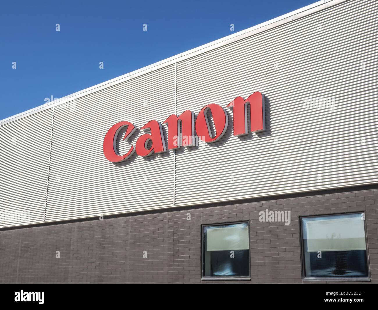 Calgary, Alberta, Kanada. April 2025. Das leuchtend rote Canon Logo hebt sich von der Wellblechverkleidung eines modernen Geschäftsgebäudes darunter ab Stockfoto