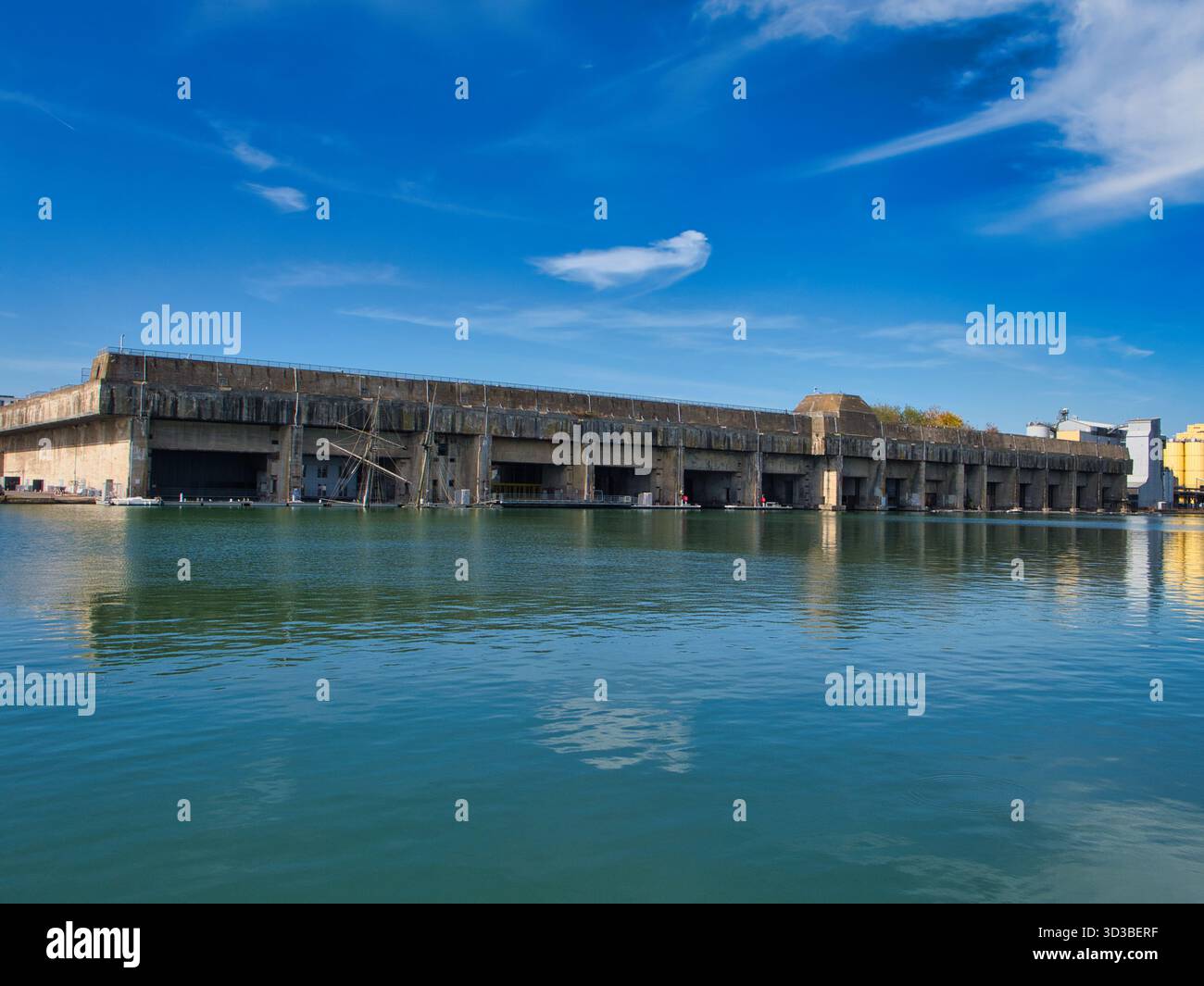 St Nazaire, Frankreich - 1. Oktober 2025: Massiver U-Boot-Bunker aus Beton spiegelt sich im Hafen von Saint-Nazaire, Frankreich, unter einem hellblauen Himmel. Historische Stätte des Zweiten Weltkriegs und Wahrzeichen am Wasser. Stockfoto