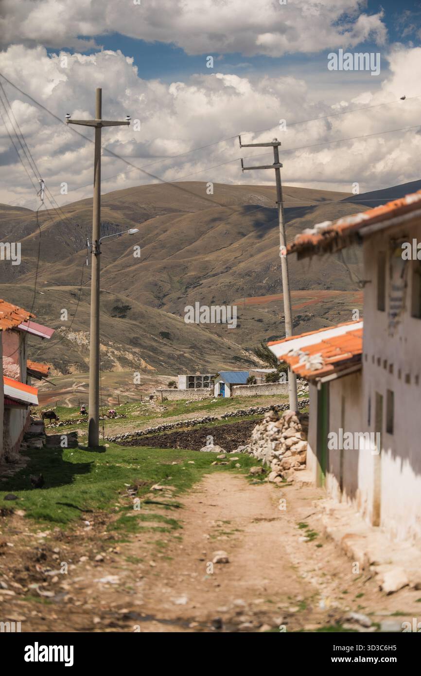 Unbefestigter Weg durch ein ländliches Andendorf mit Bergen im Hintergrund, in der Nähe von Huancayo, Peru. Stockfoto