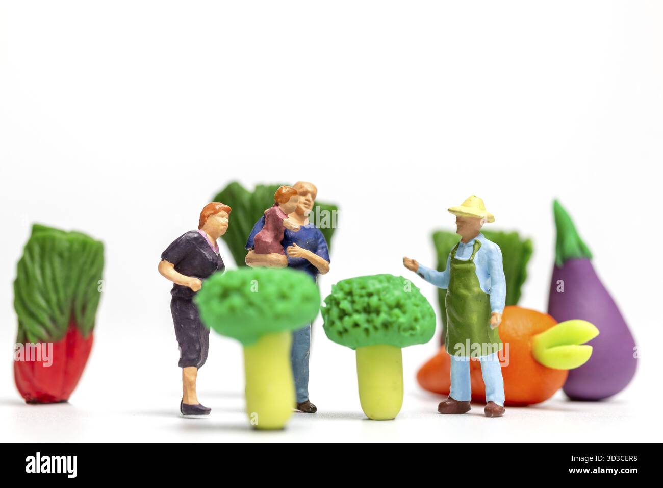 Miniaturmenschen, glückliche Familie, die auf einer Gemüsefarm ausruht. Konzept des Weltvegetarischen Tages Stockfoto