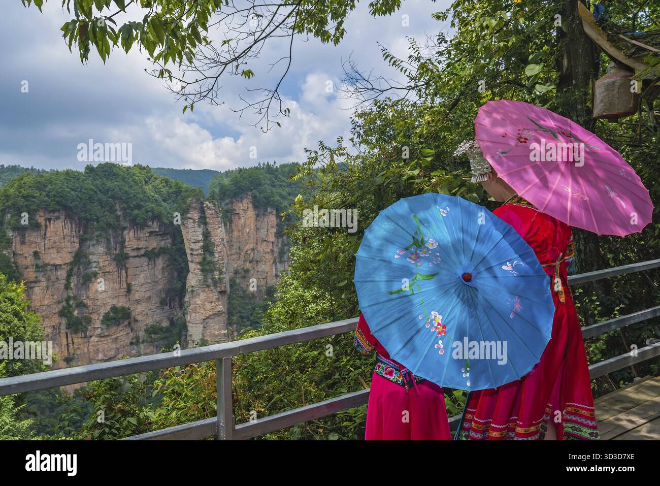 Nicht identifizierbare chinesische Frauen, die in Nationalkostümen gekleidet sind und bunte Regenschirme auf der Aussichtsplattform halten und den Avatar Berg bewundern Stockfoto