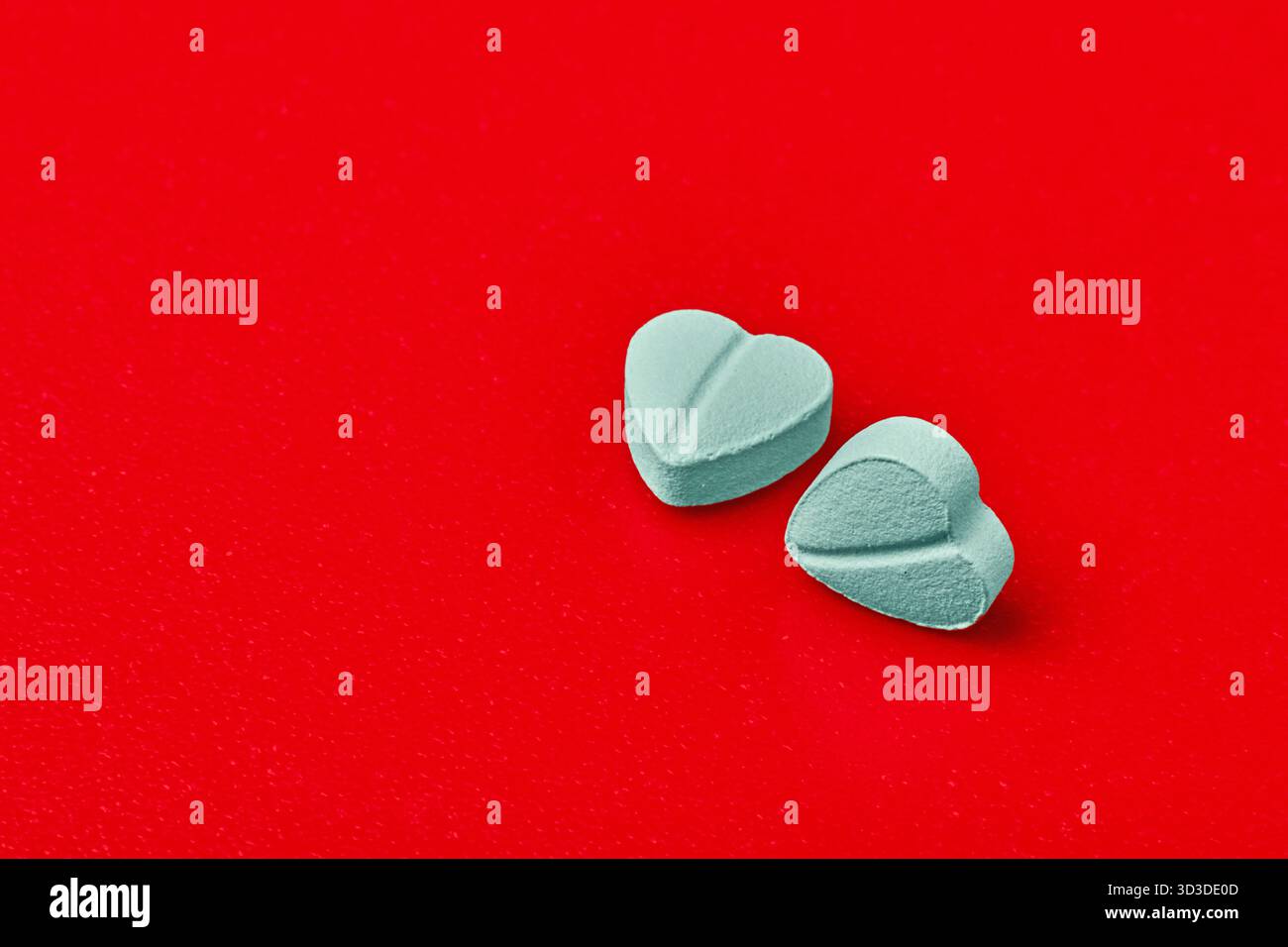 Zwei blaue Herzpillen auf rotem Hintergrund Stockfoto