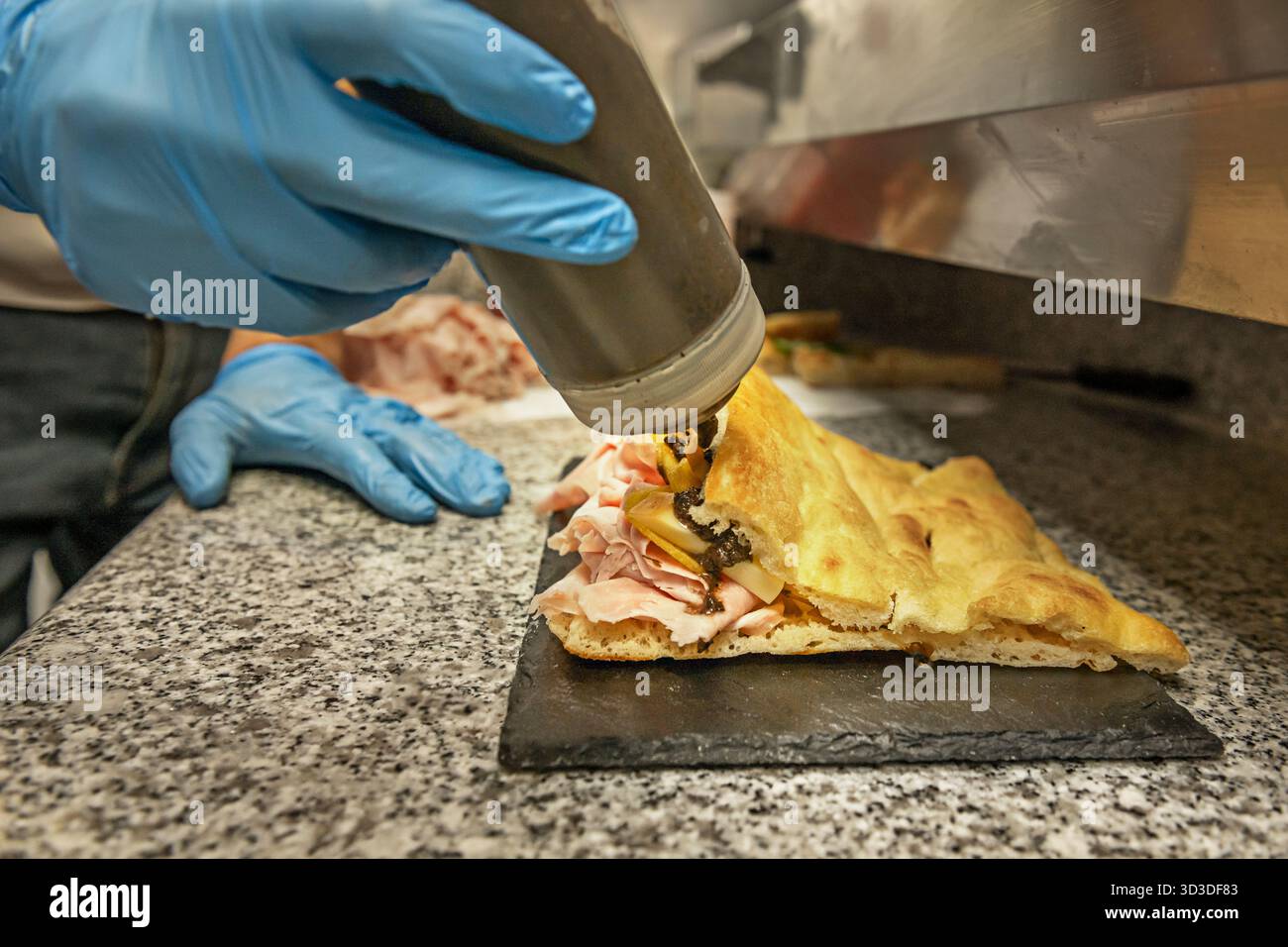 Bemehlte Finger drücken rhythmisch auf den flauschigen Focaccia-Teig und hinterlassen tiefe Einbuchtungen, die später mit extra nativem Olivenöl und fres gefüllt werden Stockfoto