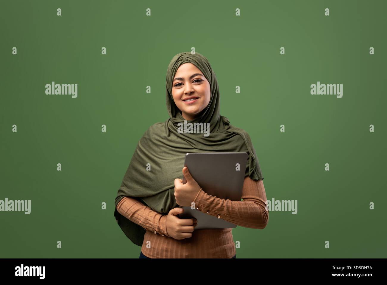 Glückliche muslimische Frau, die ein digitales Tablet in moderner Technologie verwendet Stockfoto