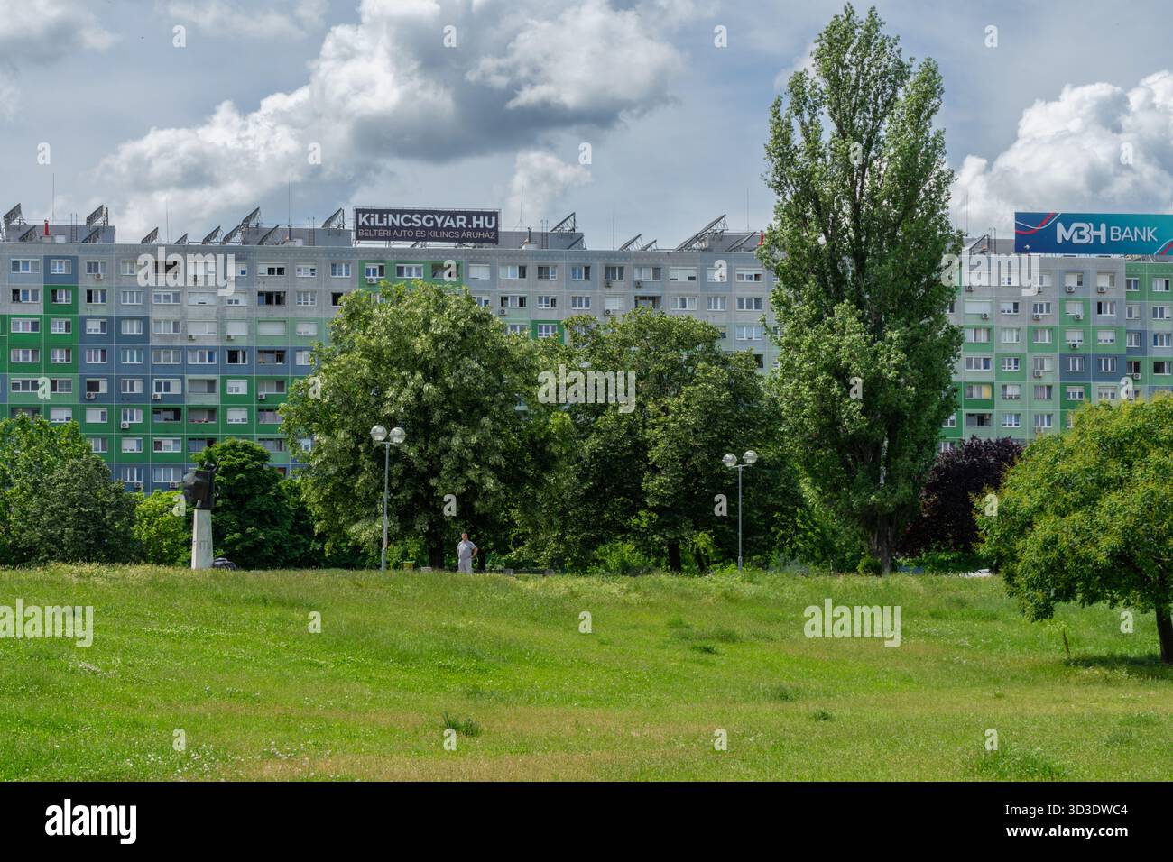 Stadtpark am Florian-Platz in Óbuda, Budapest, mit großen Blöcken hinter der grünen Fläche. Stockfoto