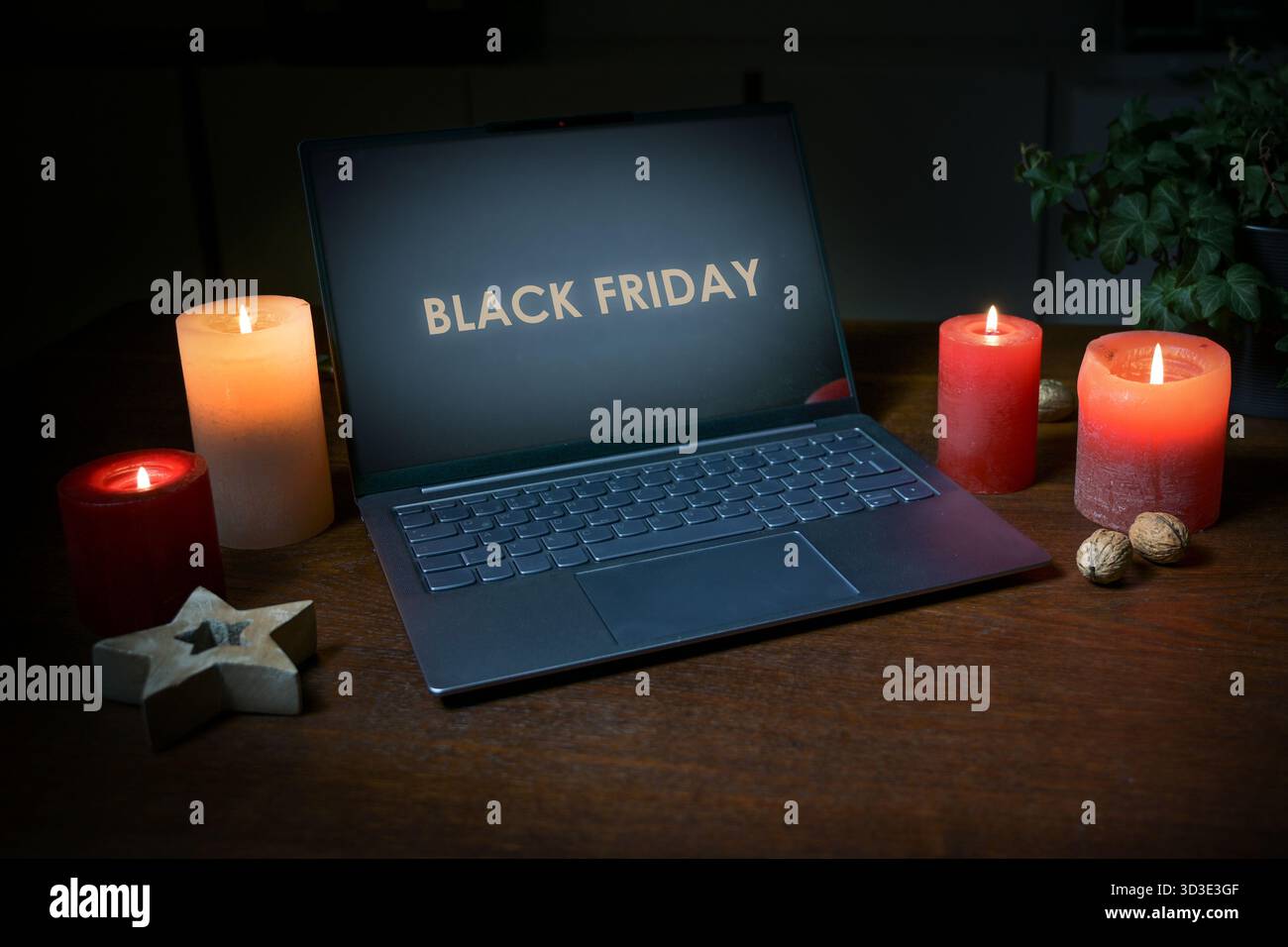 Laptop mit Text am SCHWARZEN FREITAG, Kerzen und einem hölzernen Weihnachtsstern auf einem dunkelbraunen Büroschreibtisch, Online-Shopping und Urlaubsgeschäft, Co Stockfoto