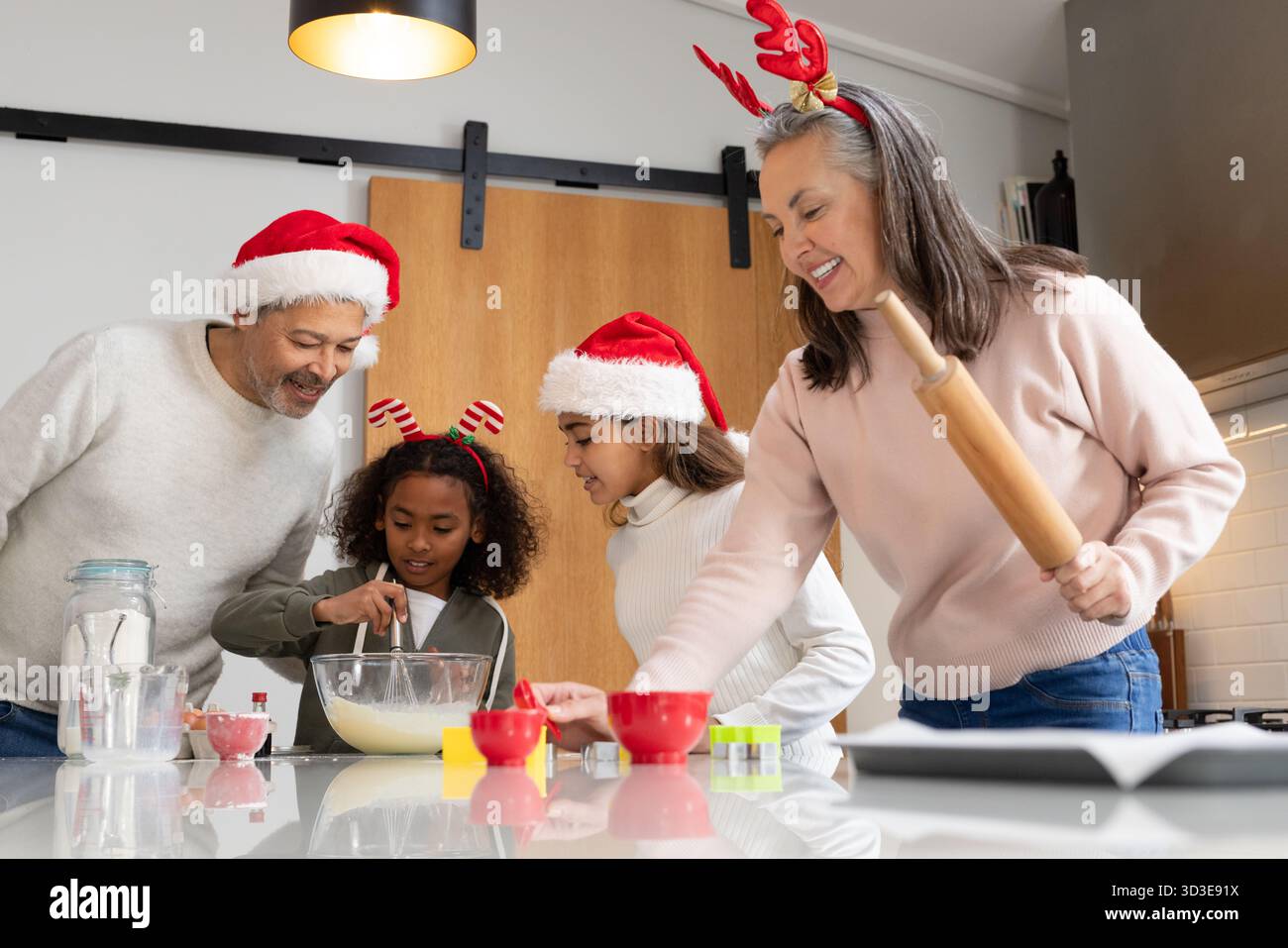 Vielfältige Familie mit Kopfbedeckung und Backkekse auf der Theke in der Küche mit Keksschneider Stockfoto