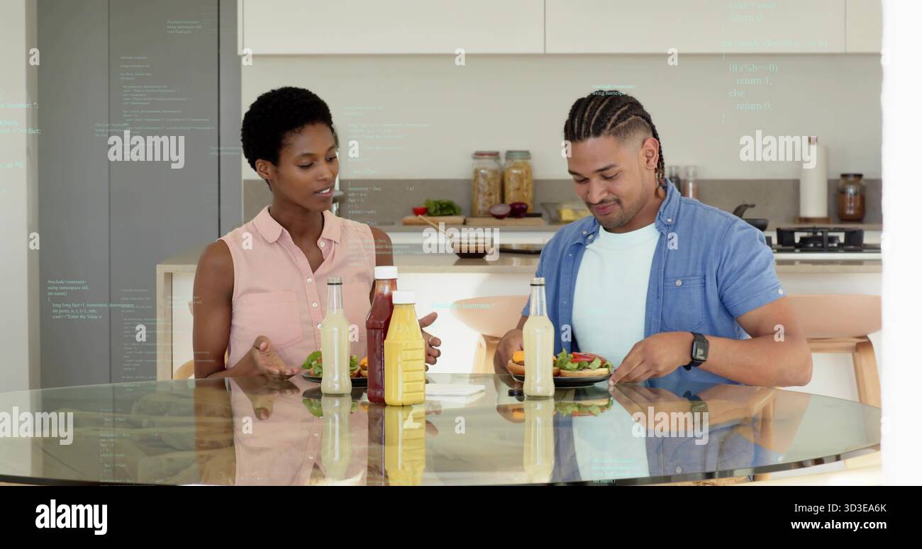 Gesten der Frau und arrangierender Mann, der frische Salate in der modernen Küche zubereitet, mit Gewürzflaschen Stockfoto