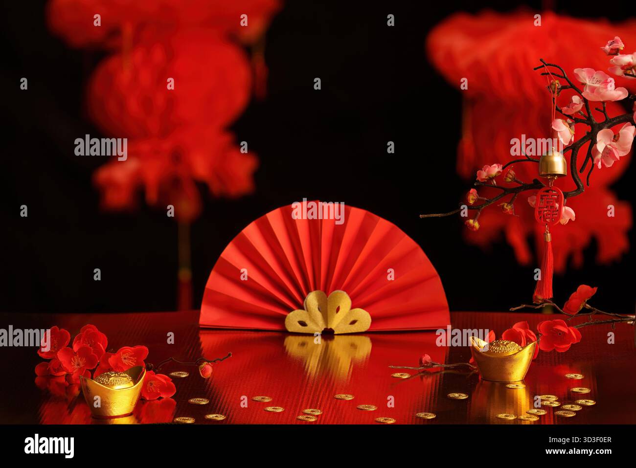 Eine auffällige Präsentation von roten Fans und Goldbarren, die Wohlstand und Glück während festlicher Feierlichkeiten symbolisieren. Stockfoto