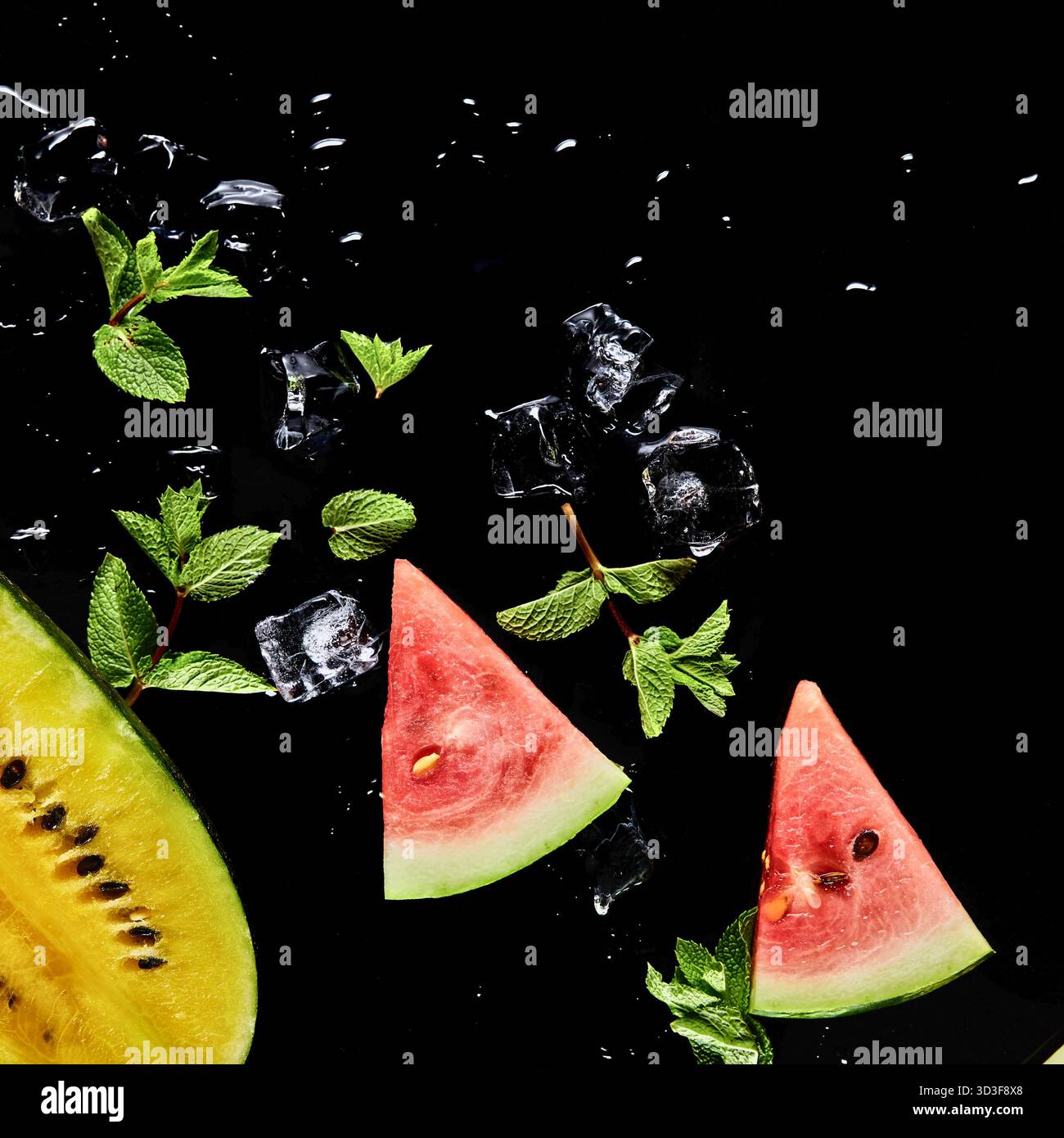 Nahaufnahme von lebendigen Wassermelonenscheiben, frischen Minzblättern und Eiswürfeln vor dunklem Hintergrund, was ein kühles, erfrischendes Getränk andeutet. Stockfoto