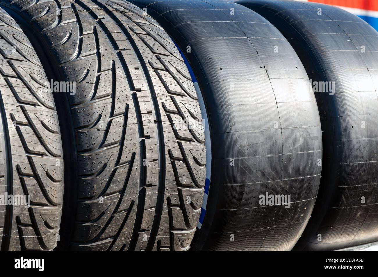 Rennreifen und Straßenreifen nebeneinander zeigen Gummi und Profil für Hochleistungsfahrzeuge Stockfoto