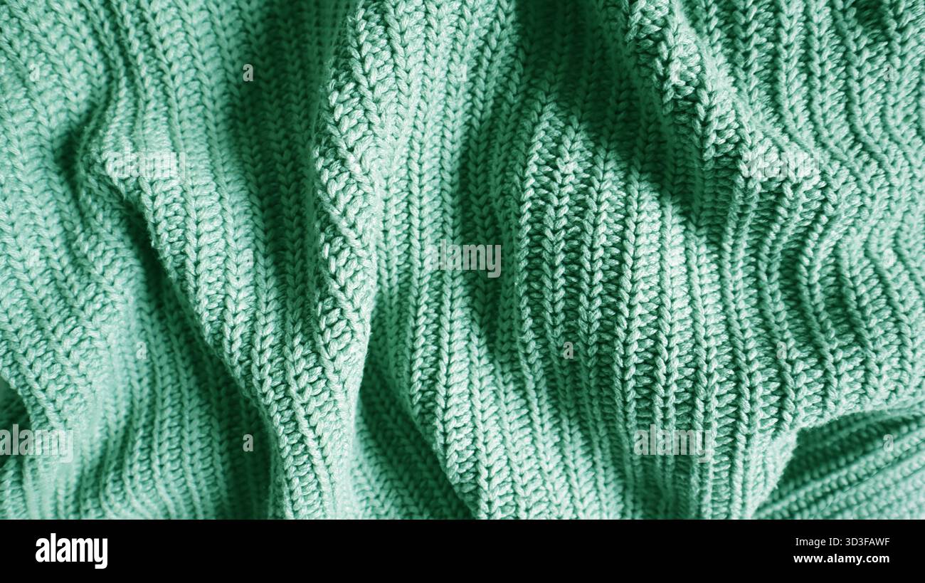 Nahaufnahme einer gestrickten Decke oder eines Pullovers in leuchtendem Mintgrün, Smaragd oder Türkis. Gemütlicher, warmer Hintergrund für Herbst, Winter oder Urlaub Stockfoto