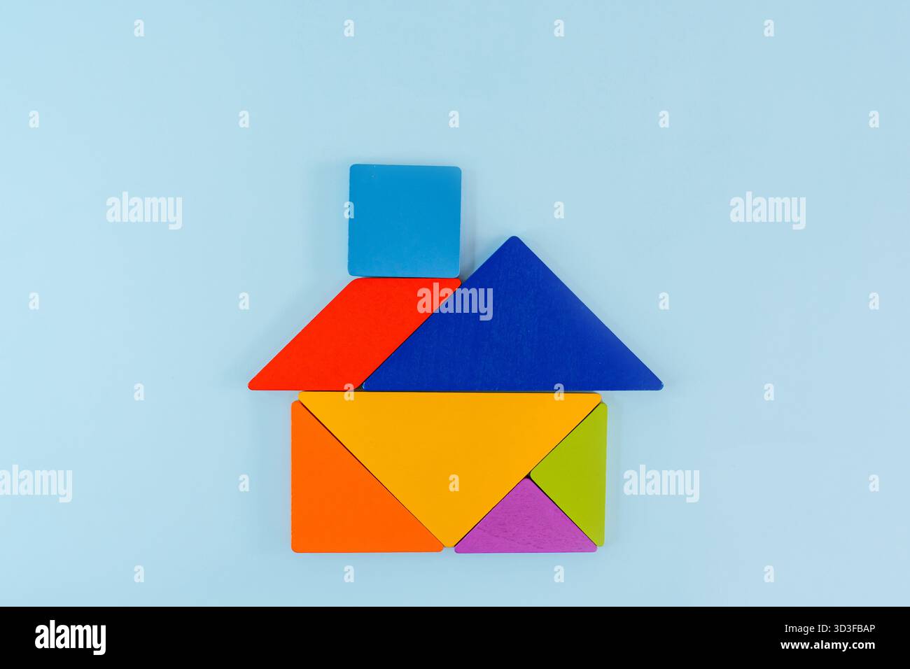 Tangram-Puzzle, das ein Haus auf blauem Hintergrund darstellt, konzeptuelles Bild Stockfoto